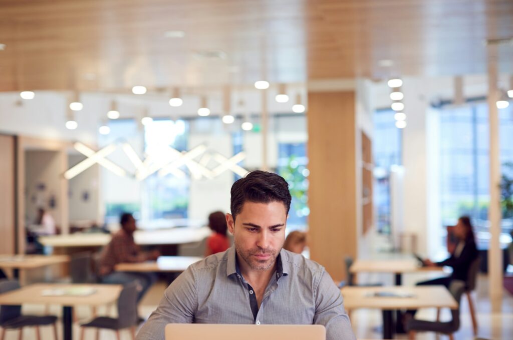 Businessman At Desk In Modern Office Work Space With Laptop