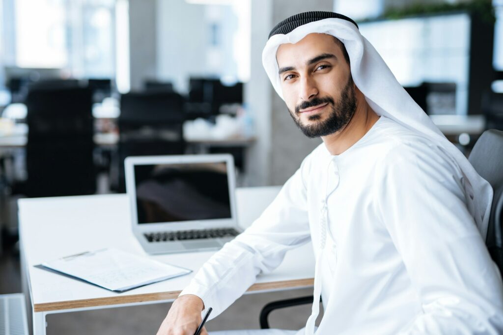 Handsome man with dish dasha working in an office of Dubai