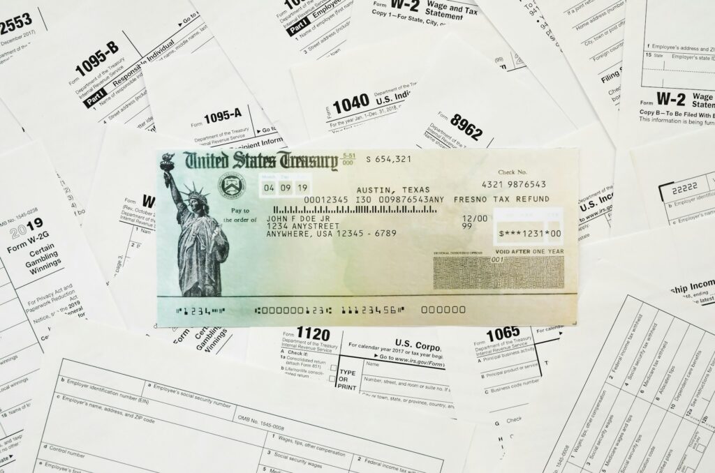 Refund check on many tax form blanks lies on table close up