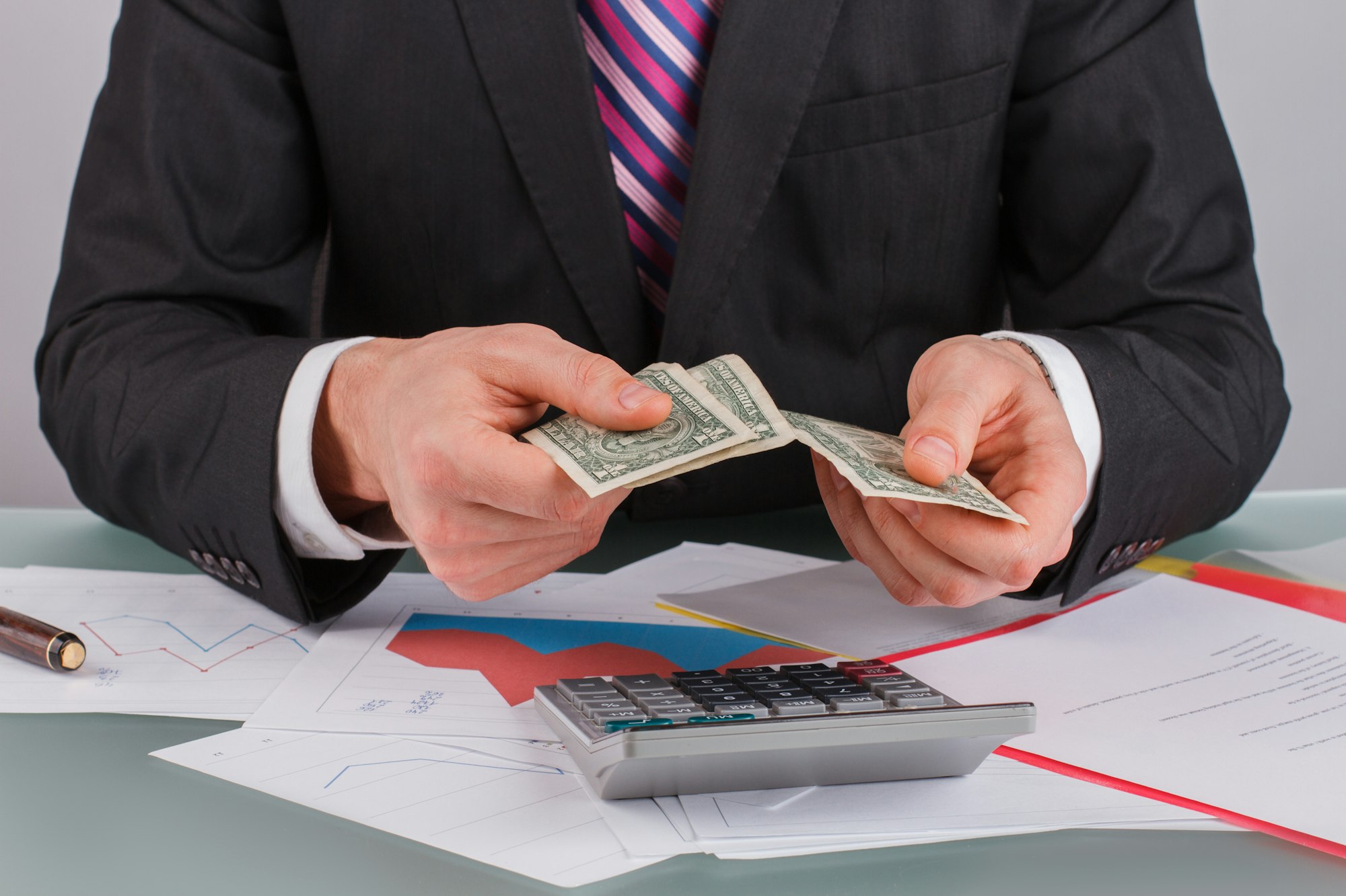 Tax accountant working with calculator and money at table.