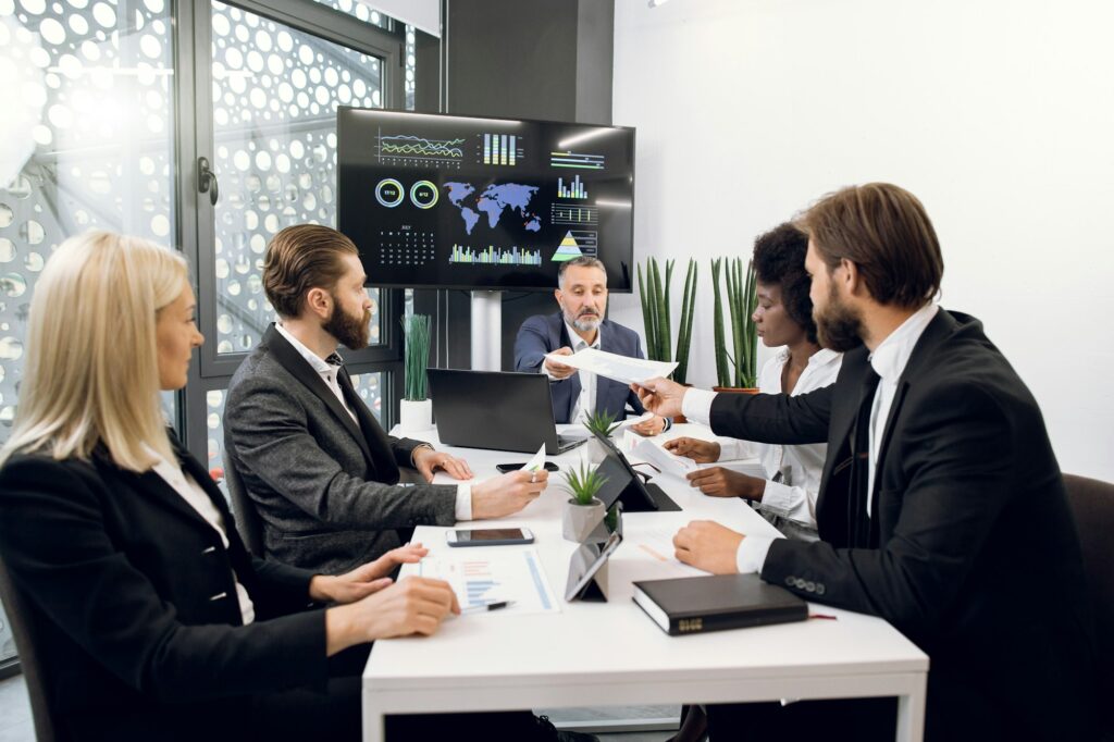 Team of international young and mature successful business people in conference room, discussing