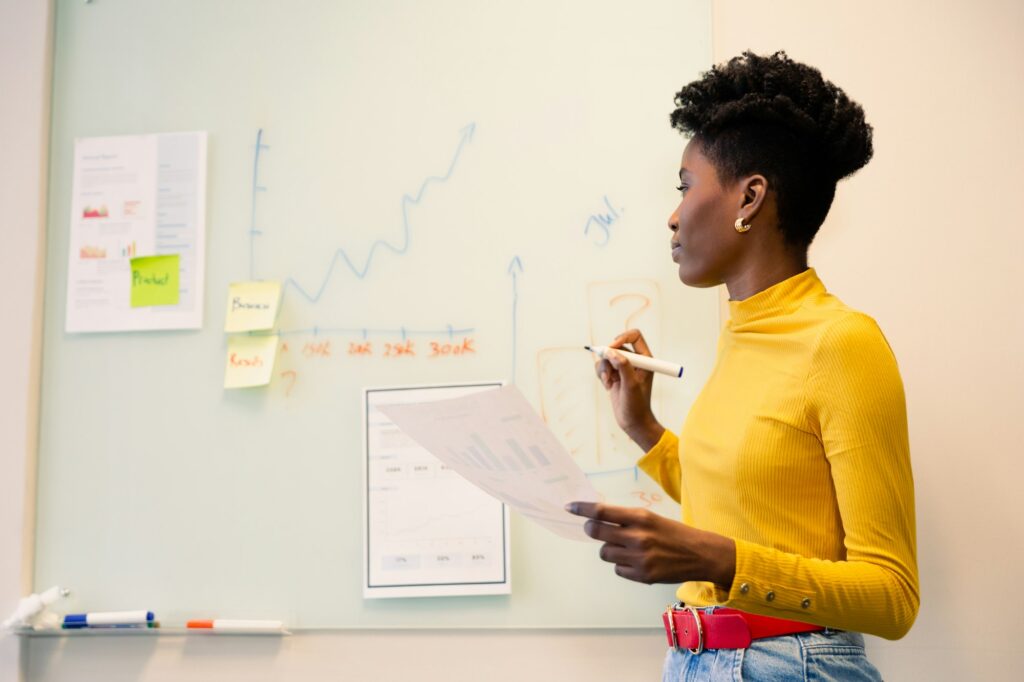 Young african american businesswoman planning strategy on whiteboard with document at workplace